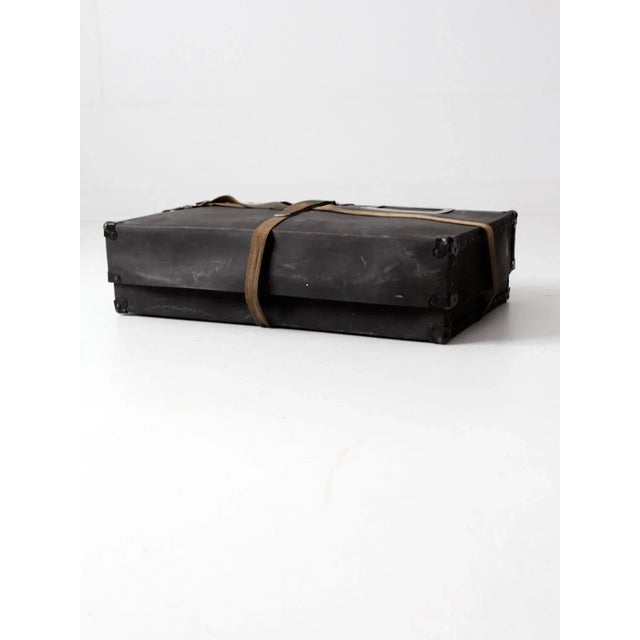 This is a vintage laundry mailing box from the early 20th century. The black fiberboard case features metal corners,...