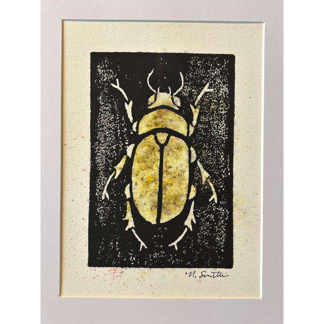 An original hand-carved block linocut featuring a detailed beetle motif, individually printed with black ink and finished...