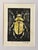 An original hand-carved block linocut featuring a detailed beetle motif, individually printed with black ink and finished...