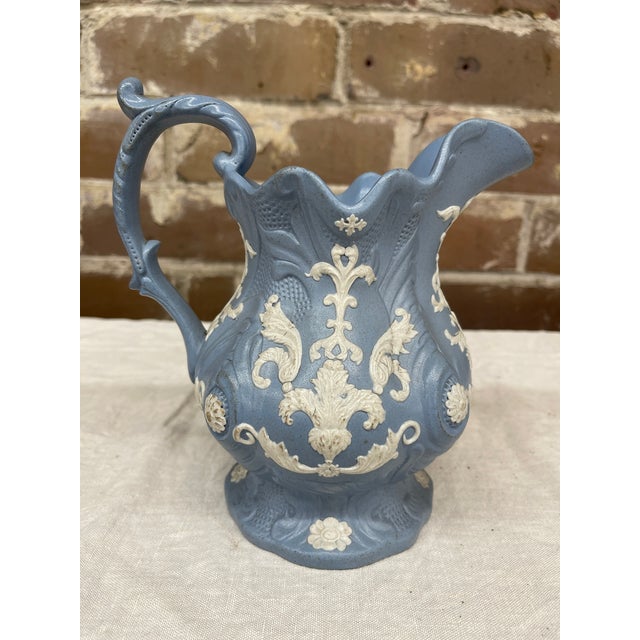 A 19th century blue jasperware pitcher with white sprigged floral and neoclassical rococo scroll on the pitcher body,...