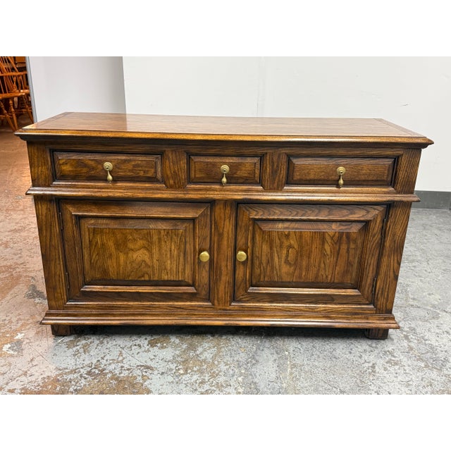 Design Plus Gallery presents an English Tudor Style Oak Wood Sideboard from Century Furniture. The oak displays pronounced...