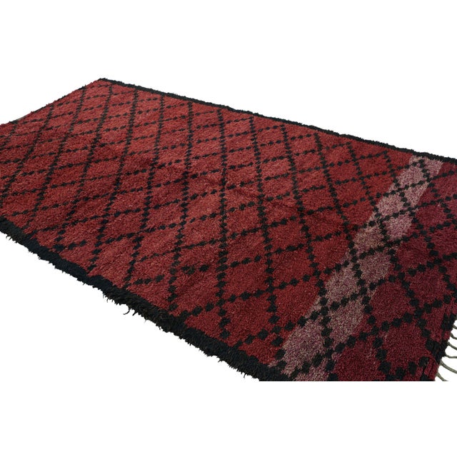 Hand-knotted in wool and originating from Morocco circa 1950-1960, this 7x10 vintage Moroccan rug is an extremely rare...