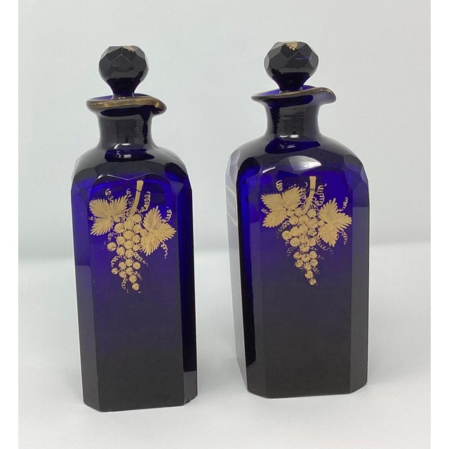 These Bristol Blue Decanters are Rum and Brandy on the front. The backs have gilt grape cluster decoration. They are 3"...