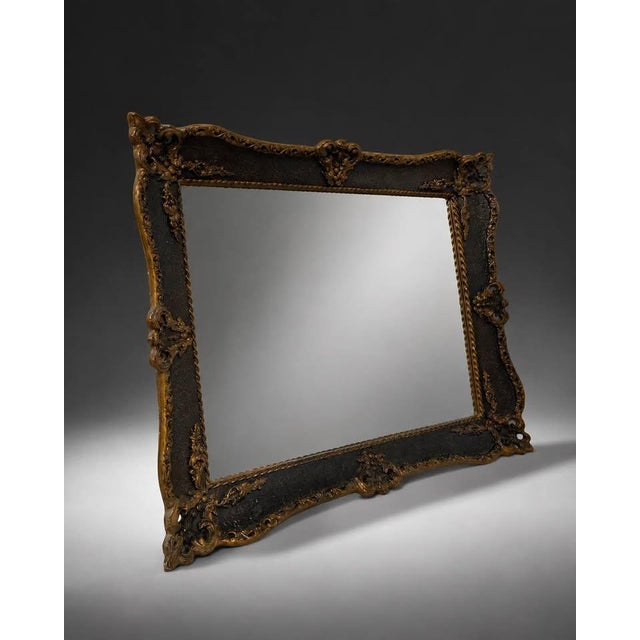Ornate decorative wall mirror featuring a black frame with antique gold detailing and carved-style scrollwork. The piece...