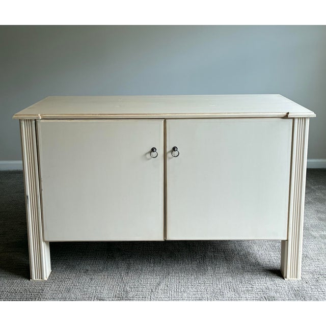 Elegant vintage cream lacquered console cabinet featuring clean architectural lines, fluted corner details, and refined...