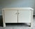 Elegant vintage cream lacquered console cabinet featuring clean architectural lines, fluted corner details, and refined...