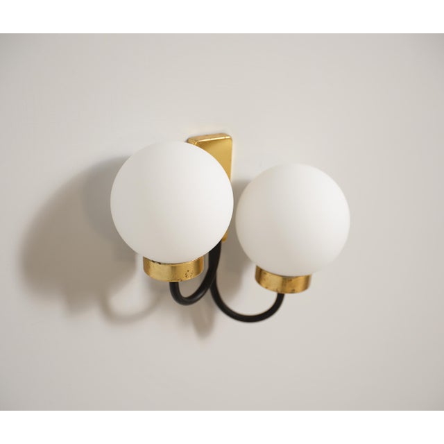 Pair of italian brass and black-enameled steel wall sconces dating to the 1950s, each formed by a rectangular backplate in...
