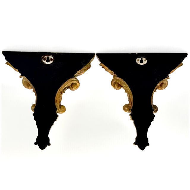 Charming pair of carved gilded wall brackets with an elegant, swirling design. The shape is fluid and decorative, with...