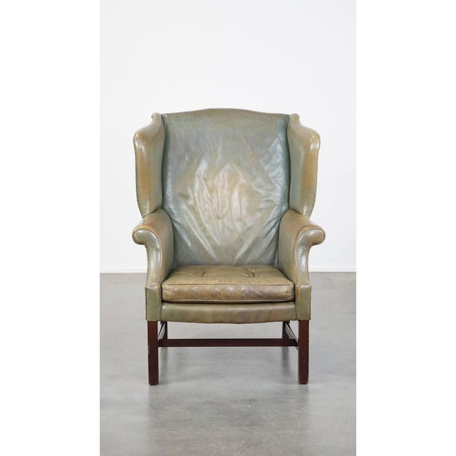 This unique and characterful green cowhide leather wing chair with a beautiful patina and correctly finished with...