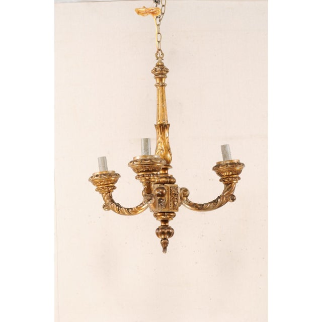A French three-light gilt and carved wood column chandelier from the mid 20th century. This vintage hanging light from...