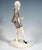 Delicate young dancer with ash-blonde, chin-length hair, wearing a grey costume comprising knee-length trousers and a...