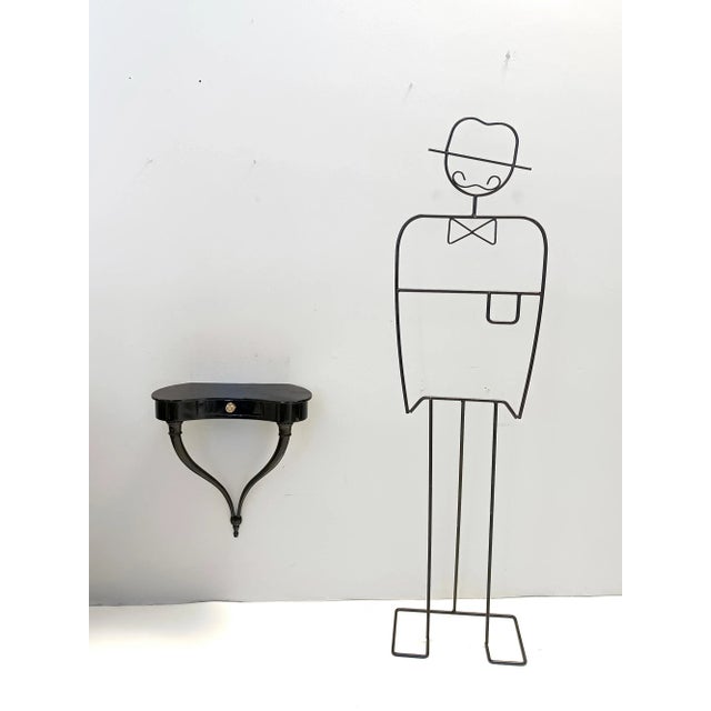 Made in Italy, 1950s. These wall-mounted console tables / nightstands feature a black beech frame with brass handles....