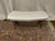 Slight kidney shaped romantic boudoir bench upholstered in a Swiss Dot Sateen fabric with ornate metal base.