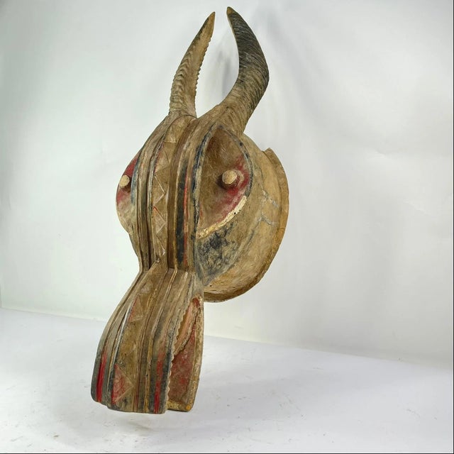 This Senufo firespitter mask is adorned with deep red and black pigments and distinguished by two imposing horns that rise...