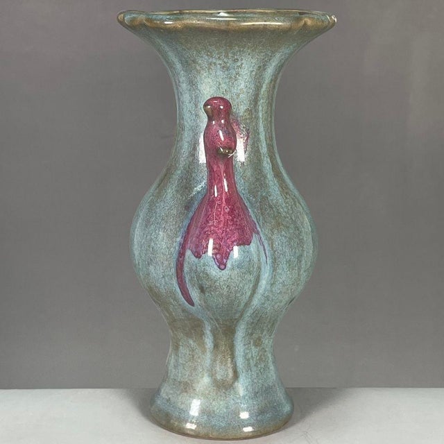 This distinctive ceramic vase features elegant peacock-form handles finished in rich plum flambe glaze against mottled...