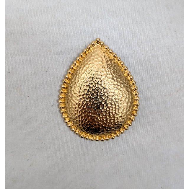 Circa 1985 "hammered" goldtone tear drop shaped brooch with nubs around the edges and security clasp. Marked "©Monet" on...