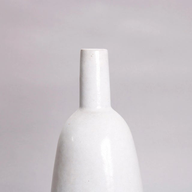 A Mid-Century Modern studio art pottery bottle vase offers bottle form with torpedo vessel, straight neck and having stone...