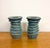 A pair of sculptural ceramic candle holders featuring stacked, undulating ridges and wide circular tops with recessed...