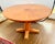 Warm, round pedestal dining table featuring a striking sunburst veneer top with a delicate inlaid ring detail. The...
