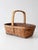 Vintage woven gathering basket featuring a wrapped handle, warm honey-brown finish, and woven accent bands that add subtle...