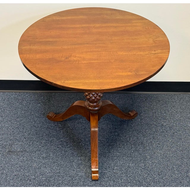charming round end table with a warm wood finish and a distinctive carved pedestal. The textured pineapple detail adds...