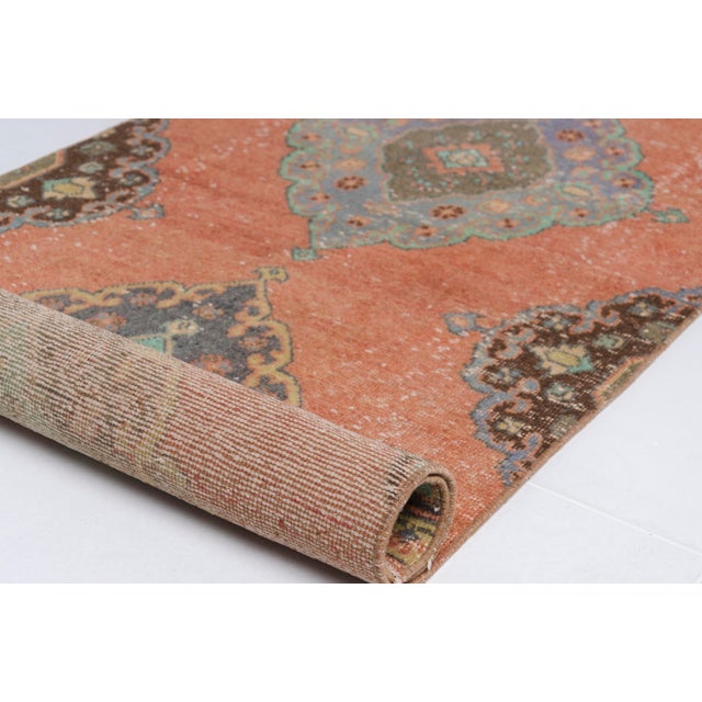 This is a vintage Turkish Oushak rug from the Mid 20th Century. The piece was hand-knotted.