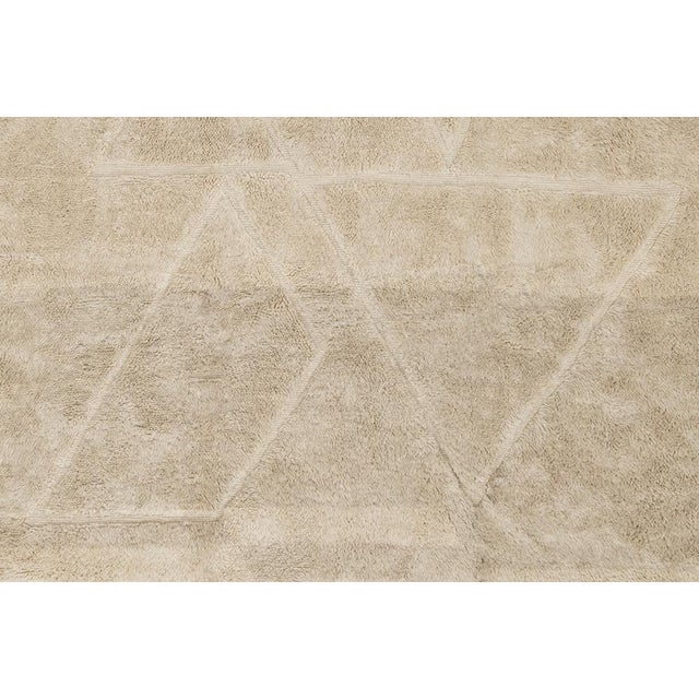 Natural hand-knotted wool rug in warm Cream Beige and light Ancient Grain with subtle geometric triangle patterns. The...
