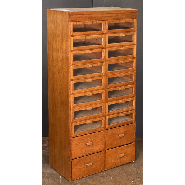 A handsome vintage double haberdashery or haberdasher's cabinet of patinated oak, with paneled sides from England...