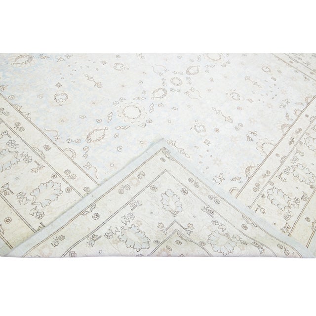 Beautiful antique Persian Tabriz style hand-knotted wool rug with a light blue field. This piece has a beige frame and...