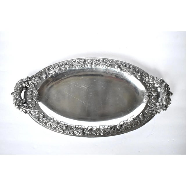A vintage oblong serving platter with an ornate raised design of acorns and oak leaves around the border and handles; with...