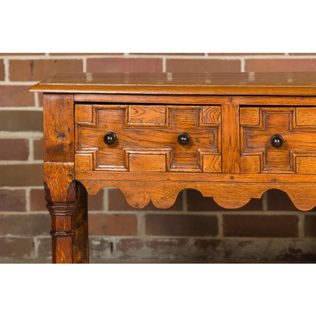 An English oak geometric front server from the 19th century with three drawers, carved apron and column carved legs. Delve...