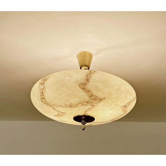 Large Art Deco pendant light with a mottled ivory beige glass shade with darker veins, mounted on a brass rod and canopy...