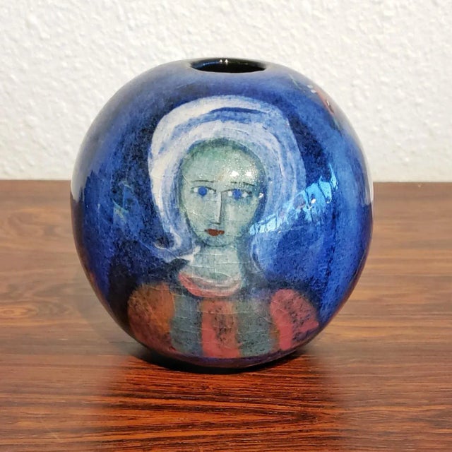 A beautiful hand-painted ball vase featuring a typical motif of animals and a woman on a blue ground by renowned Polish-...