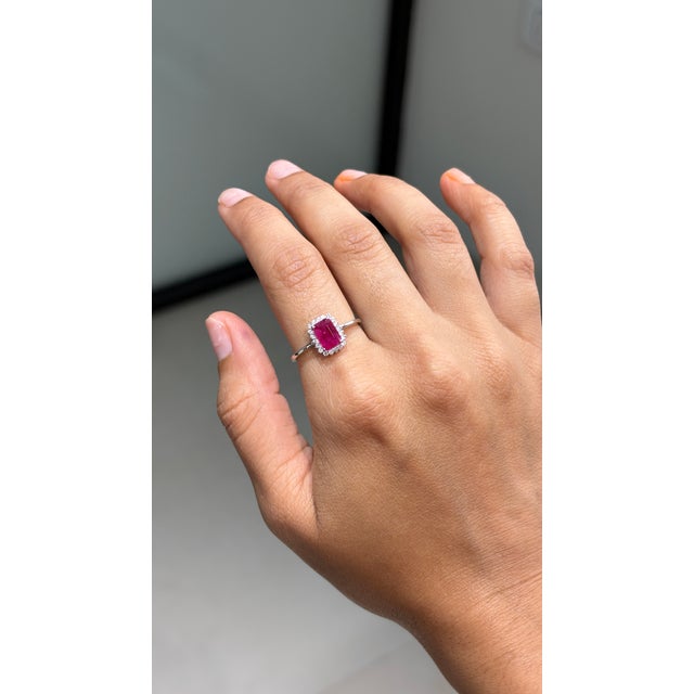 This modernist halo engagement ring showcases a vivid 1.05 ct emerald-cut ruby, set in 14k white gold. The ruby measures 7...
