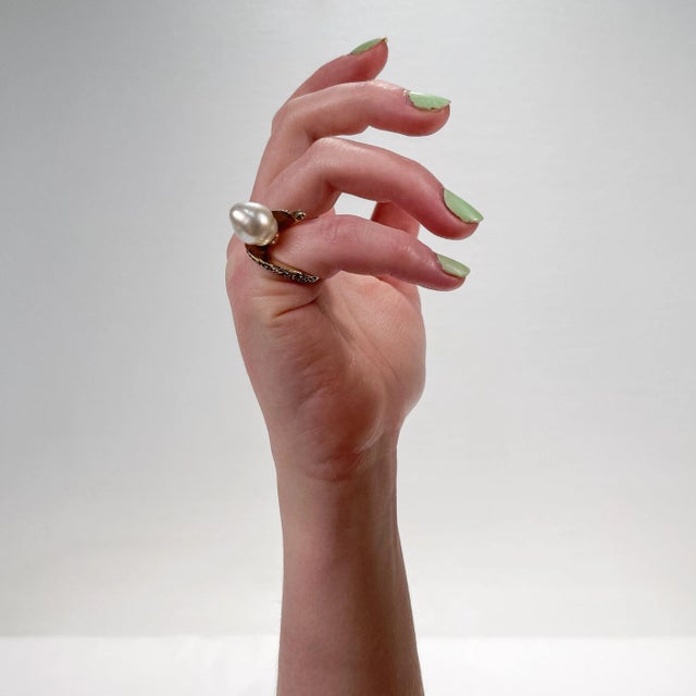 A very fine Brutalist cocktail ring. In 14k yellow gold. Set with a large grey baroque pearl in shaped & textured...