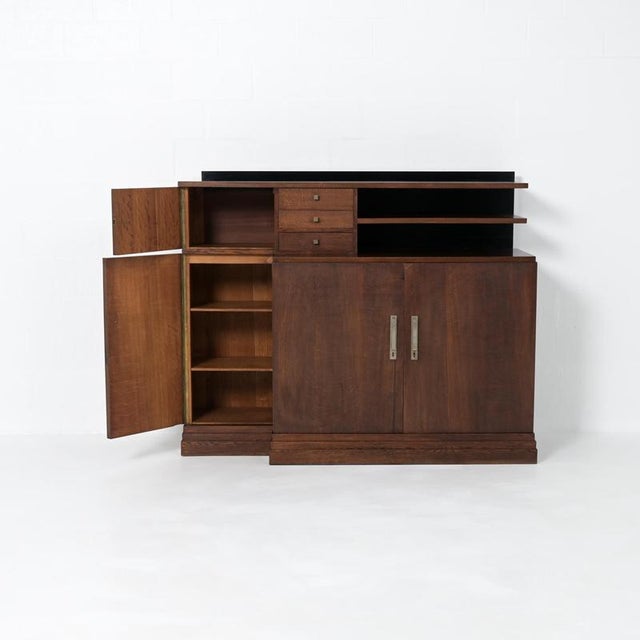 A beautiful Belgian modernist cabinet in oak, with a black-ebonized back panel and elegant handles made of chrome-plated...