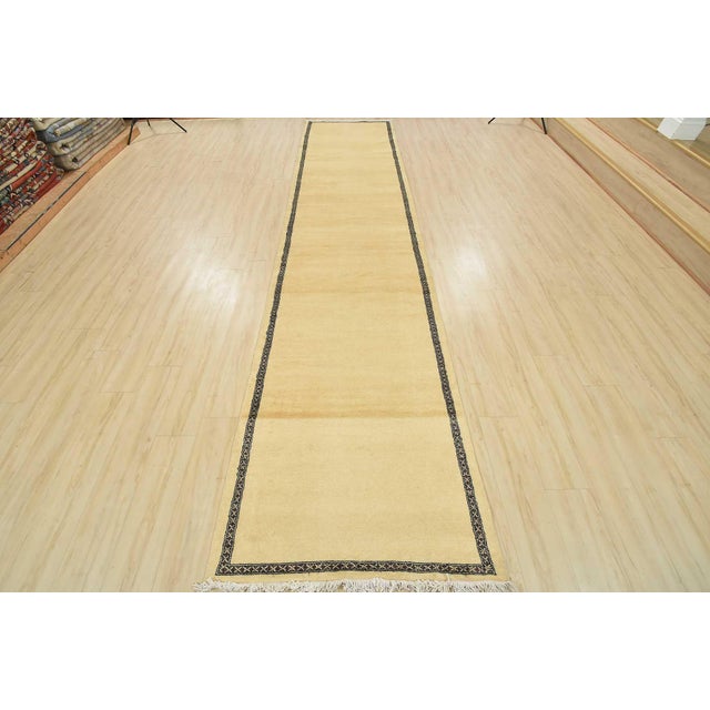 A tribal Bokhara runner hand-knotted with an all-wool pile on a cotton foundation. This finely woven oriental rug features...