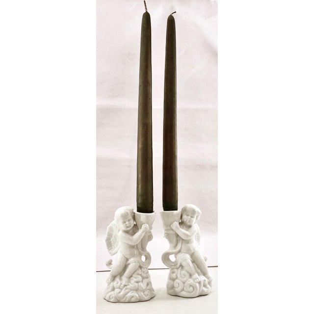 A pair of creamy white glazed porcelain putti formed with fluid detail. Set a beautiful tablescape with these angelic...