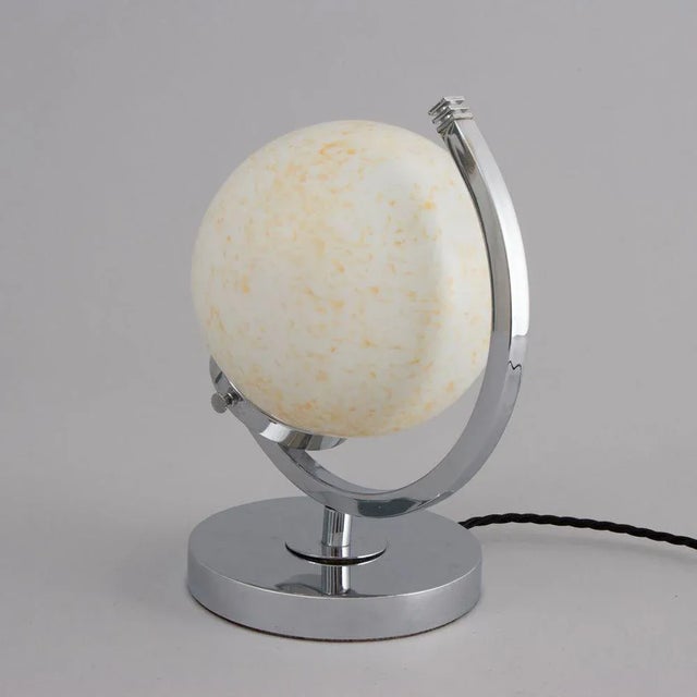 H: 25cm w: 21cm d: 15.5cm a british art deco table lamp with a central mottled glass globe shade and a chrome half-moon...