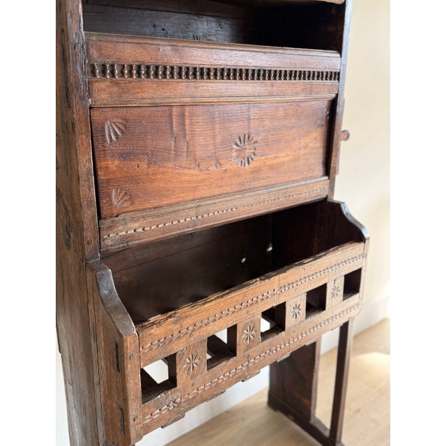 A French kitchen vaisselier in dark carved chestnut, gone nearly black at the edges from old wax. An open plate rack with...
