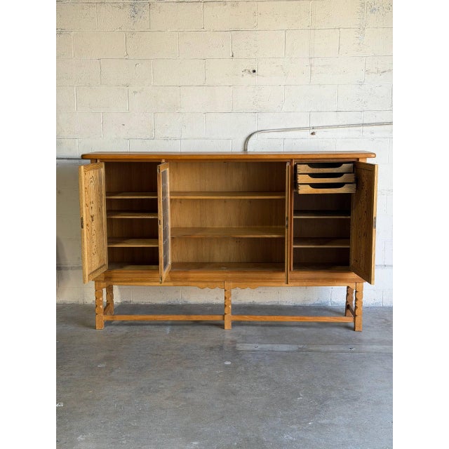 This large oak sideboard in style of Henning Kjærnulf presents a balanced four-door facade. Two central leaded glass doors...