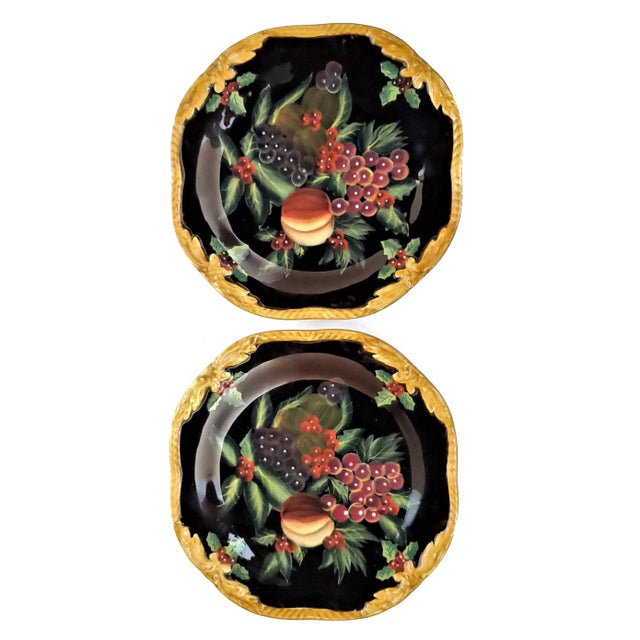 Offering a pair of ceramic salad plates adorned with grapes, peaches, and green leaves on a black background with a beige...