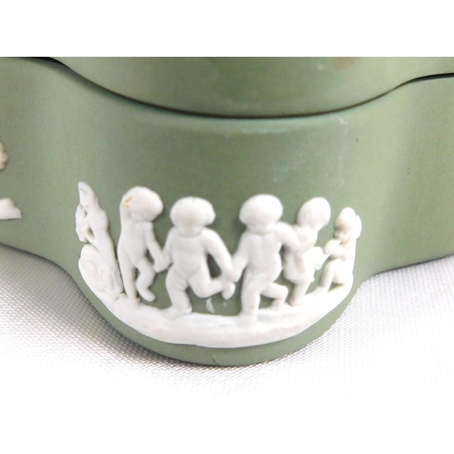 This is a Wedgwood Jasperware trinket box with lid in Celedon. It is kind of loosely star shaped. The box has a design on...