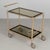 An Italian Hollywood Regency style brass plated bar cart. Smoked glass shelves with dark paned border. Simple bar handle....