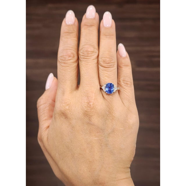 A captivating 3.50-carat GIA-certified cushion-cut sapphire ring, featuring a vibrant blue hue, flanked by two GIA-...