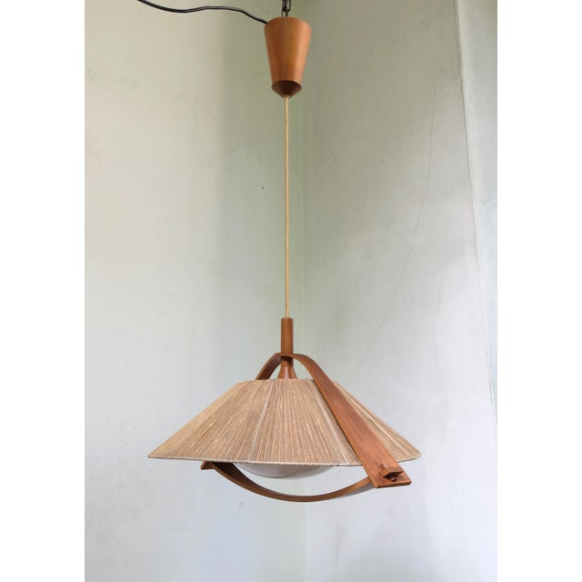 Ceiling lamp from the 1960s by Temde made of teak, plexiglass, and a cord shade. The lamp emits a pleasant, glare-free...