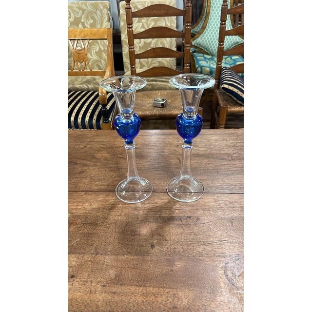 An elegant blown glass candlestick holder featuring a clear flared bobeche and round pedestal base, highlighted by a rich...