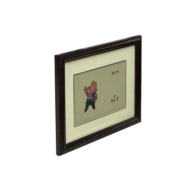 This vintage framed artwork features a charming, hand-crafted depiction of a pig character, rendered in a style...