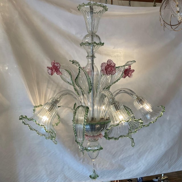 A stunning, highly decorative Venetian glass chandelier featuring hand-blown floral elements and elegantly curved glass...