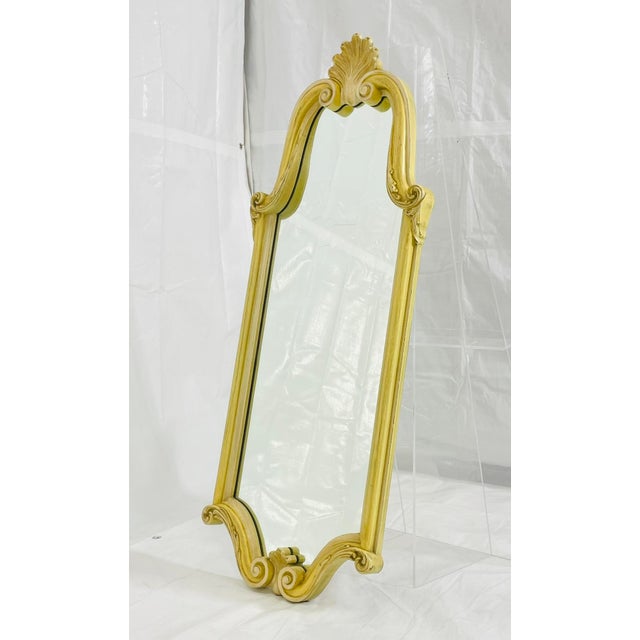 An elegant and highly decorative vintage wall mirror dating to the 1940s, crafted in carved wood with a warm gilt finish...